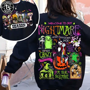 May include: A black sweatshirt featuring a colorful graphic print of characters from The Nightmare Before Christmas. The design includes Jack Skellington, Sally, Oogie Boogie, and text that reads Welcome to our Nightmare and I'm your nightmare.