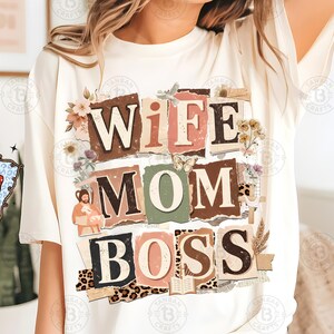 May include: Cream-colored t-shirt with the words "WIFE MOM BOSS" in a collage style. The design incorporates floral elements, a butterfly, and a leopard print pattern. The shirt is a casual, everyday wear item.