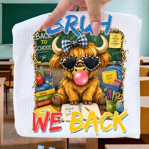 May include: A white t-shirt featuring a graphic of a fluffy highland cow wearing a blue plaid bow and heart-shaped sunglasses while blowing a pink bubble. The design includes school supplies, a chalkboard, and the text BRUH WE BACK.