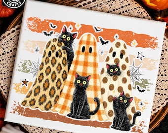 May include: A rectangular canvas print featuring three black cats wearing ghost costumes with leopard, plaid, and polka dot patterns. The background includes orange horizontal stripes, spider webs, stars, and bats. The Tanban Crafts logo is in the corner.