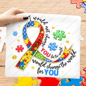May include: A white t-shirt featuring a large awareness ribbon made of colorful patterned fabric with red roses and a pearl-like border. The text reads: I would not change YOU for the world, would change the world for YOU, surrounded by puzzle pieces.