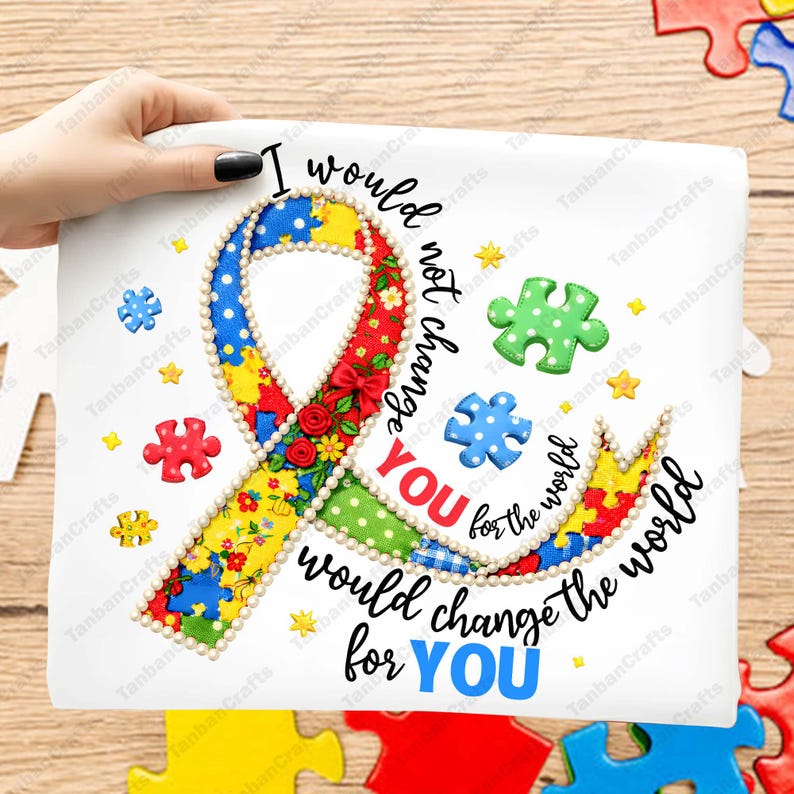 May include: A white t-shirt featuring a large awareness ribbon made of colorful patterned fabric with red roses and a pearl-like border. The text reads: I would not change YOU for the world, would change the world for YOU, surrounded by puzzle pieces.