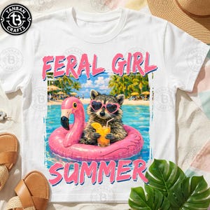 May include: White t-shirt with a graphic of a raccoon wearing heart-shaped sunglasses and floating on a pink flamingo floatie. The text "FERAL GIRL SUMMER" is in pink. The raccoon is holding a drink.