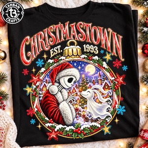 Peut inclure: Un t-shirt noir avec une illustration d'un squelette en costume de Père Noël et d'un chien fantôme. Le texte indique CHRISTMASTOWN EST. 1993. Le motif est encadré par une boule de Noël, du houx, des étoiles et des flocons de neige.