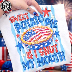 May include: A white t-shirt featuring a graphic of a pie with an American flag pattern on the crust. The text reads SWEET POTATO PIE & I SHUT MY MOUTH in red and blue lettering. The design includes red and blue stars against a light blue wavy background.