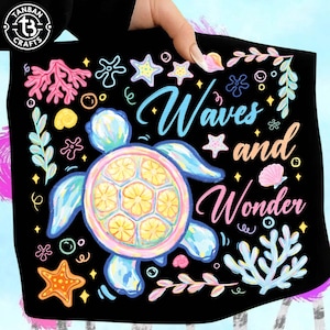 May include: Black beach towel with a colorful illustration of a sea turtle, starfish, and coral. The towel has the words "Waves and Wonder" in a whimsical font. The towel is held up by a hand.