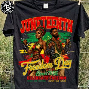 May include: Black t-shirt with a graphic celebrating Juneteenth. The design features a man and woman holding chains, with the words "Juneteenth" and "Freedom Day" in red and yellow. Text reads "Since 1865, Celebrate Freedom, Honor Our Heritage, Inspire Our Future."
