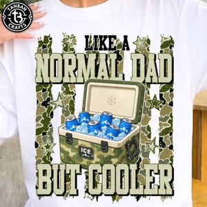 May include: White t-shirt with a camouflage design and the text "LIKE A NORMAL DAD BUT COOLER". The graphic includes an open cooler filled with ice and blue cans.