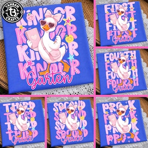 May include: A blue t-shirt featuring a white duck wearing a pink bow and heart-shaped sunglasses, carrying a pink notebook and bag. The design includes colorful stars, apples, and text such as Kinder, First, Second, Third, Fourth, and Pre-K Grade.