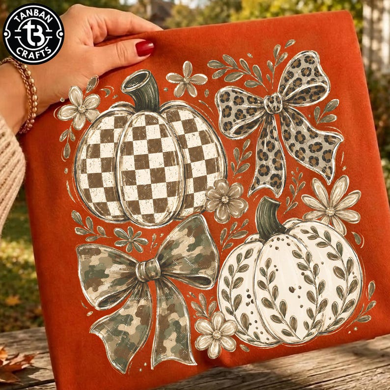 May include: A burnt orange fabric featuring a graphic print of two pumpkins, one with a white and brown checkered pattern and one with a white leaf design, accompanied by a leopard print bow, a camouflage bow, and several small white flowers.