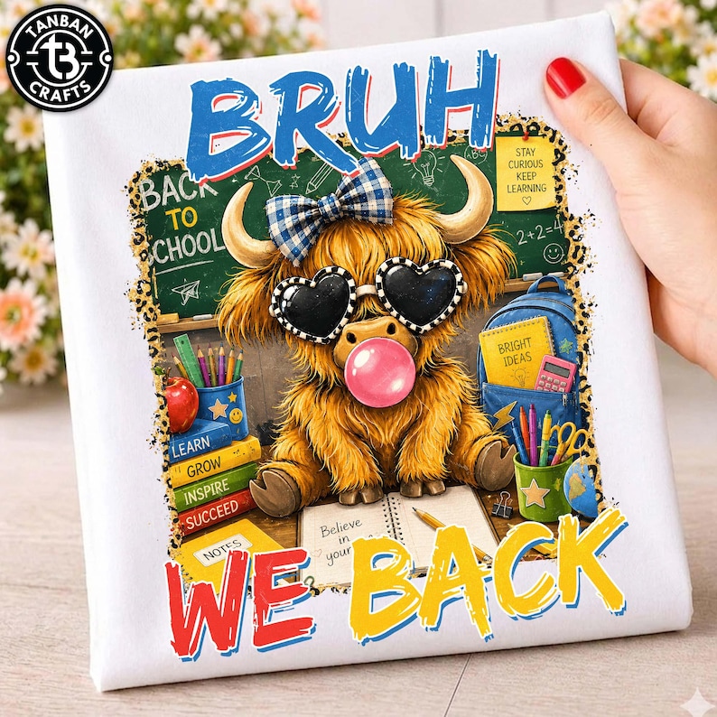 May include: A white fabric item featuring a graphic of a fluffy highland cow wearing a blue plaid bow and heart-shaped sunglasses while blowing a pink bubble. The text reads BRUH WE BACK, with school supplies, a chalkboard, and a blue backpack.