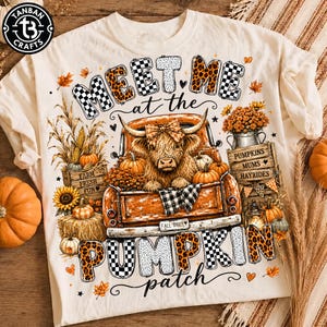 May include: A cream-colored t-shirt featuring a graphic of a highland cow in an orange pickup truck. The text reads "MEET ME at the PUMPKIN patch" and "FALL VIBES". The design includes pumpkins, sunflowers, hay bales, and crates labeled "FARM FRESH FUN" and "PUMPKINS MUMS HAYRIDES".
