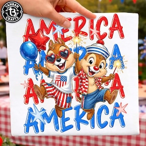 Könnte beinhalten: Ein weißes T-Shirt mit einer Grafik von zwei Zeichentrick-Streifenhörnchen, die mit Wunderkerzen und Luftballons feiern. Der Text AMERICA ist in Rot und Blau wiederholt. Ein Streifenhörnchen trägt eine Herzbrille, das andere eine Matrosenmütze.