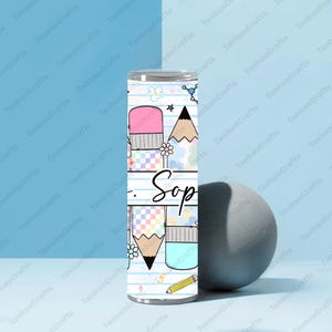 May include: A stainless steel tumbler with a school-themed design. The design includes pencils, erasers, and the word "Sop" in a handwritten font. The tumbler is decorated with pastel colors and floral accents.