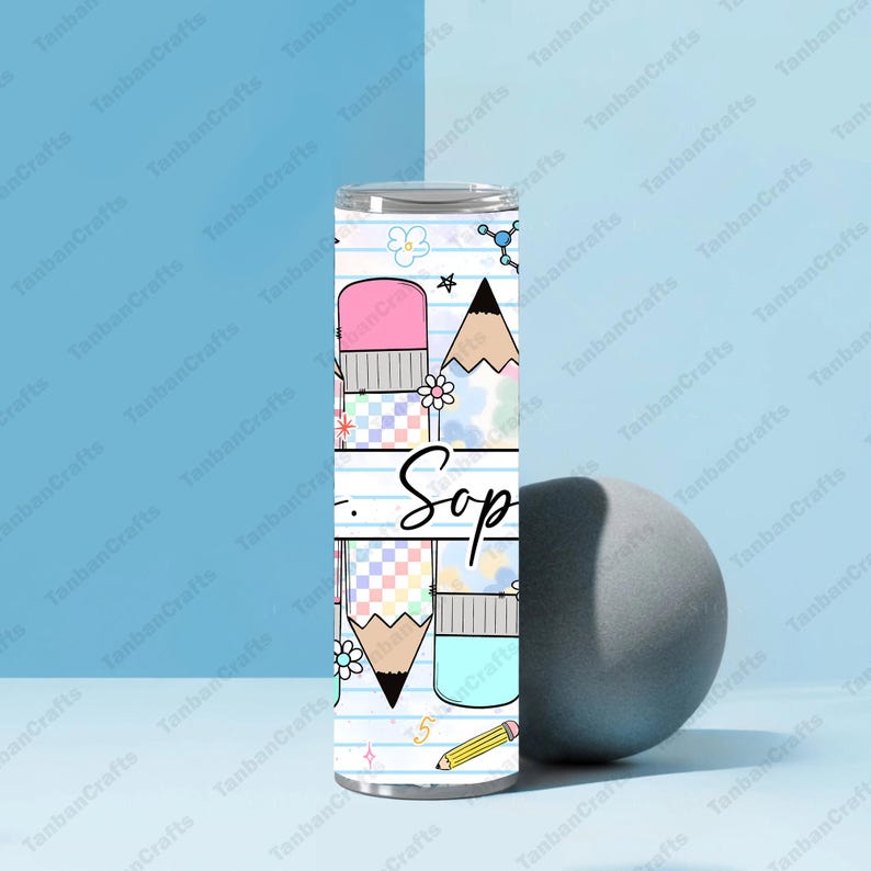 May include: A stainless steel tumbler with a school-themed design. The design includes pencils, erasers, and the word "Sop" in a handwritten font. The tumbler is decorated with pastel colors and floral accents.