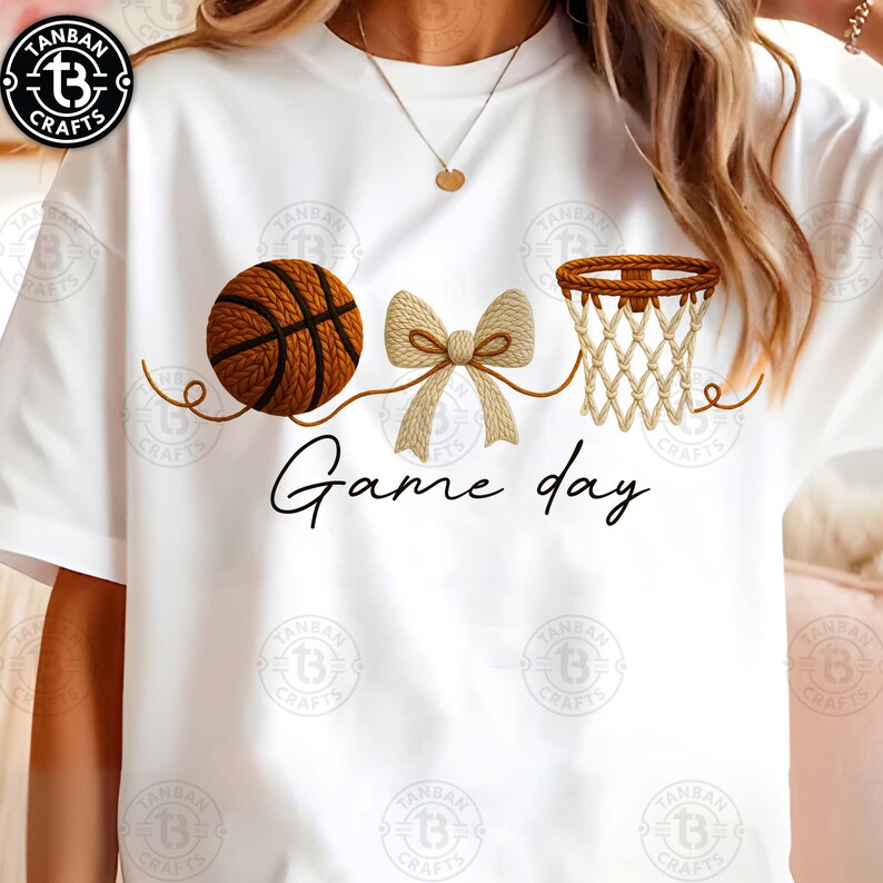May include: White t-shirt with a basketball, bow, and basketball net graphic. The words "Game day" are written in a script font below the graphics. The basketball is brown with black lines.