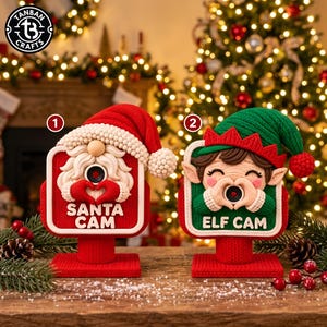 May include: Two decorative holiday camera ornaments on stands. The first is a red Santa figure with a white beard and hat, labeled SANTA CAM. The second is a green elf figure with a pointed hat, labeled ELF CAM. Both feature a central lens.