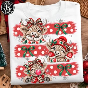 May include: A white sweatshirt featuring a graphic print of three fluffy Highland cows. The cows are decorated with leopard print bows, red and green Christmas sweaters, mittens, and scarves. The design includes red polka dot stripes and green bows.