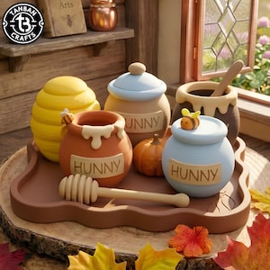 May include: A collection of ceramic honey pots on a brown tray, including a yellow beehive-shaped pot, a terracotta pot labelled HUNNY with a bee, a blue pot labelled HUNNY with a bee, a brown pot with a wooden dipper, and a small orange pumpkin.