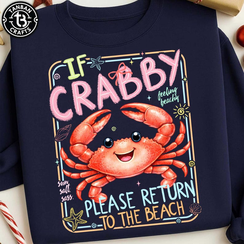 Może przedstawiać: Granatowa bluza z nadrukiem z kresk&oacute;wkowym krabem. Grafika zawiera napis "If Crabby, Please Return to the Beach" w zabawnej czcionce, a także uśmiechniętego kraba, rozgwiazdy i muszle.