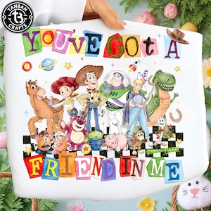 Può includere: Borsa tote bianca con la scritta "YOU'VE GOT A FRIEND IN ME" in lettere colorate. La borsa presenta illustrazioni dei personaggi della serie di film Toy Story, tra cui Woody, Buzz Lightyear e altri.