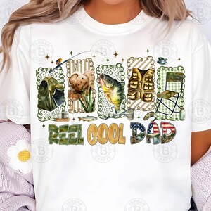 Op de afbeelding: Wit T-shirt met een visserij-thema ontwerp. Het ontwerp bevat illustraties van visgerei, een vis en de tekst "REEL COOL DAD". De letters zijn gevuld met patronen en kleuren, waaronder de Amerikaanse vlag.