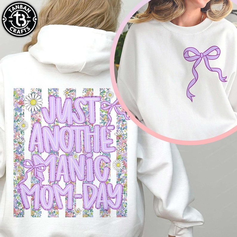 May include: White hoodie and sweatshirt with a purple bow design. The hoodie features the text "JUST ANOTHER MANIC MOM-DAY" in purple, with a floral and striped background. The sweatshirt has a single purple bow.