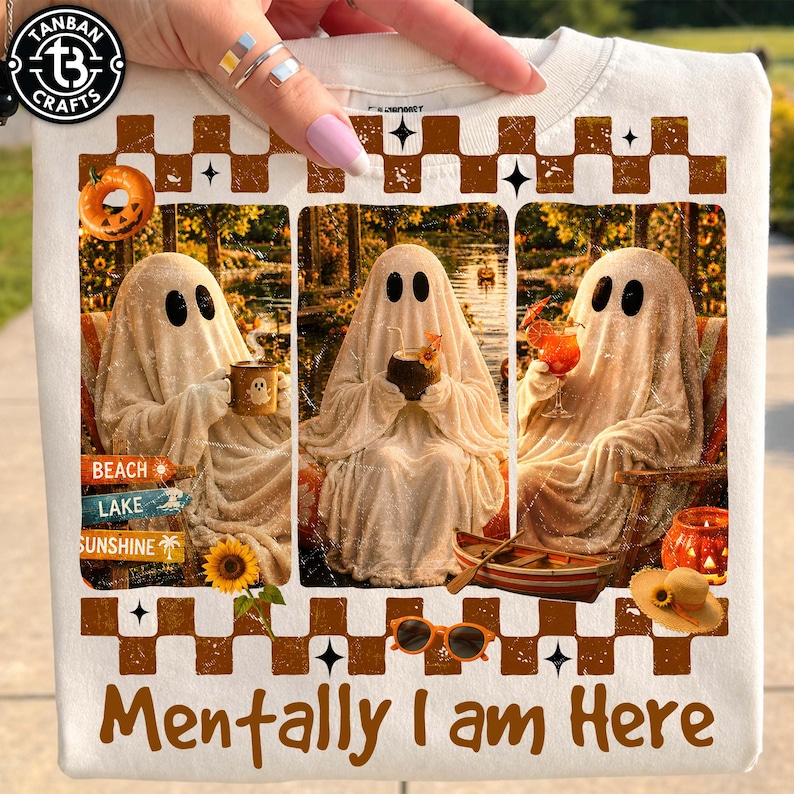 May include: White t-shirt with a graphic of three ghosts relaxing with drinks, a pumpkin, and the text "Mentally I am Here." The design includes a brown checkered pattern and the words "Beach, Lake, Sunshine."