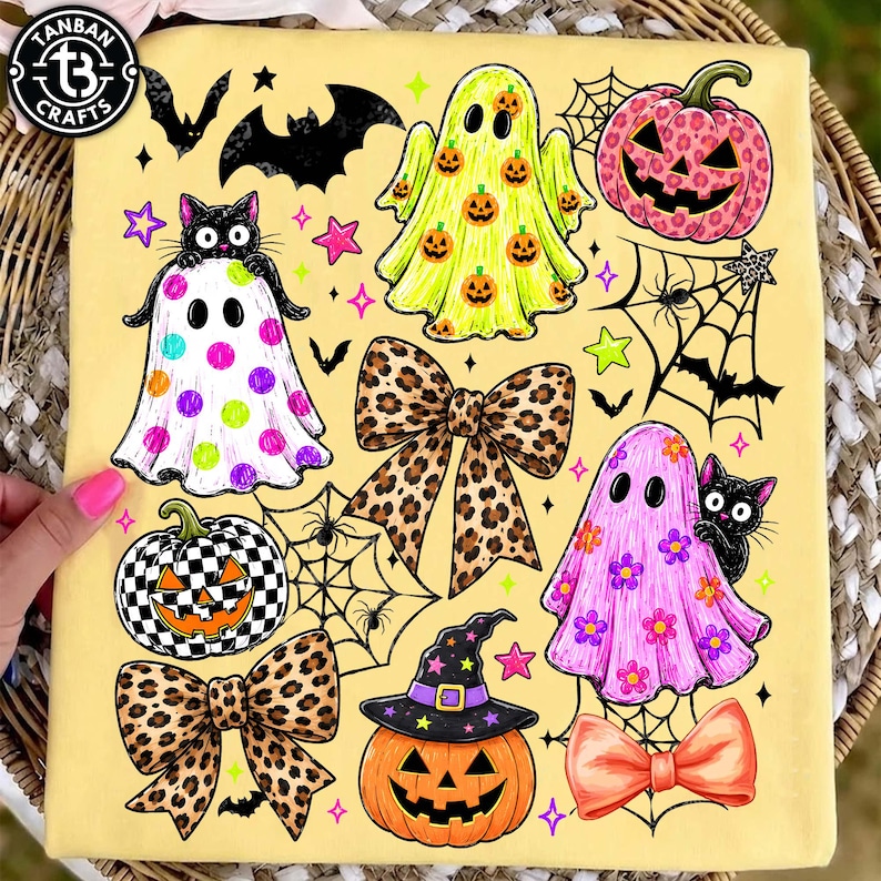 May include: A pale yellow fabric featuring a Halloween-themed graphic print. The design includes ghosts with pumpkin, polka dot, and floral patterns, jack-o'-lanterns with leopard and checkerboard prints, leopard print bows, and black cats.