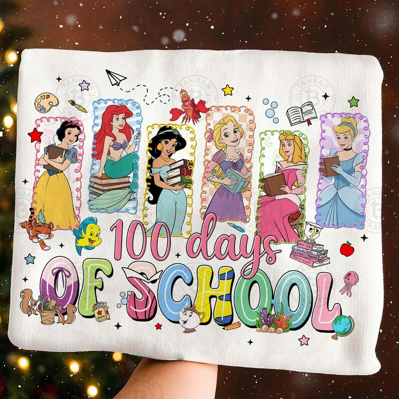 May include: White t-shirt featuring Disney princesses with books, celebrating "100 days of school." The design includes Ariel, Jasmine, Belle, Aurora, and Cinderella, with colorful text and decorative elements.