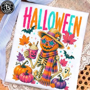 May include: A white t-shirt featuring a colorful graphic of a skeleton wearing a straw hat, star-shaped sunglasses, and a scarf. The skeleton holds a pumpkin-themed mug. The design includes pumpkins, bats, a ghost, and autumn leaves with the text HALLOWEEN.