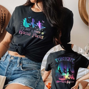 Puede incluir: Camiseta negra con la frase "It's just a bunch of Hocus Pocus" y un gr&aacute;fico de tres brujas volando en escobas. La parte trasera de la camiseta tiene el texto "Tonight We Fly" con un gr&aacute;fico similar.
