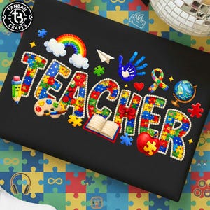 May include: Black t-shirt with the word "TEACHER" in colorful puzzle piece letters. The design includes a rainbow, handprint, ribbon, globe, and other school-themed graphics. The shirt has the "TANBAN CRAFTS" logo in the upper left corner.