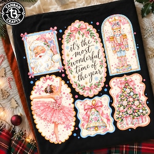 May include: A black t-shirt featuring a festive graphic print with five framed illustrations: Santa Claus, a nutcracker, a ballerina in a pink tutu, a decorated bell, and a Christmas tree, with the text it's the most wonderful time of the year.