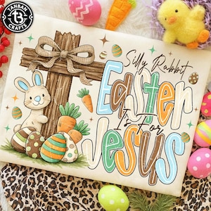 May include: A cream-colored Easter-themed graphic with a cross, bunny, and eggs. Text reads "Silly Rabbit Easter Is For Jesus." Carrots and a bow are also featured. The image is surrounded by Easter decorations.