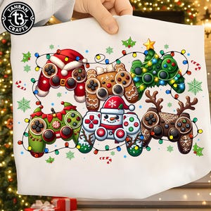 May include: A white fabric surface featuring a graphic print of six video game controllers decorated for the holidays. The controllers are styled as a Santa suit, gingerbread cookie, Christmas tree, elf, snowman, and reindeer, all connected by string lights.