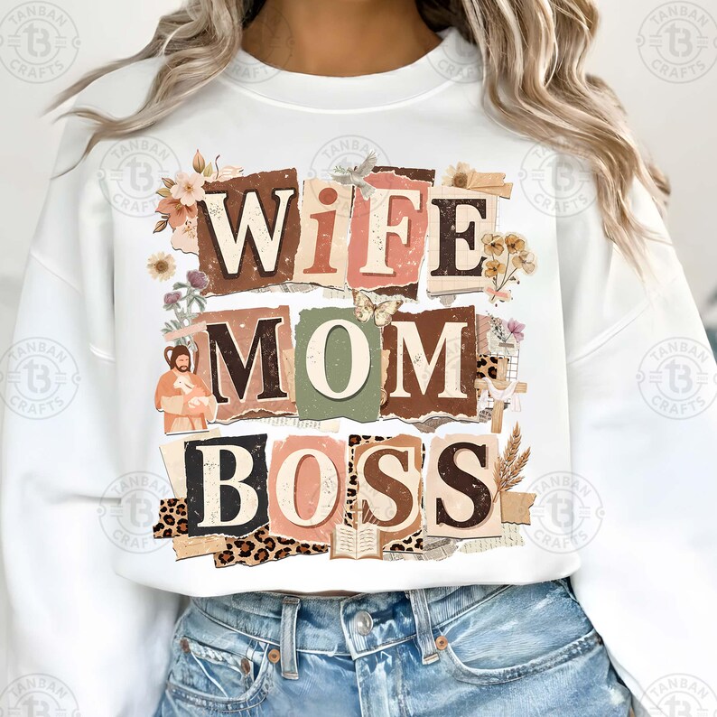 May include: White sweatshirt with the words "WIFE MOM BOSS" in a collage style design. The design incorporates floral elements, a butterfly, and torn paper textures. The sweatshirt is a casual, everyday wear item.