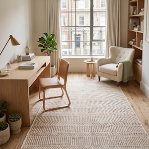 May include: A home office space featuring a light wood desk, a tan leather chair, and a large rectangular area rug with a textured, repeating geometric pattern in cream and beige tones, positioned on a light oak hardwood floor.