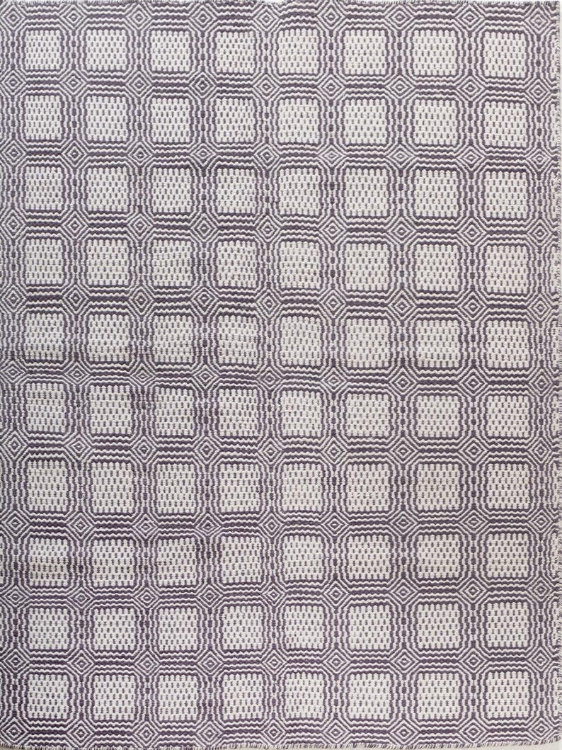 May include: A woven textile featuring a repeating geometric pattern of dark purple and off-white squares. The design consists of small, textured rectangles arranged in a grid, framed by thin, interconnected diamond shapes that create a structured, symmetrical appearance across the entire surface of the fabric.