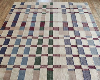 May include: A woven rug with a checkered pattern in shades of beige, blue, green, and burgundy.