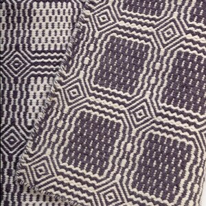 May include: A woven textile featuring a repeating geometric pattern in dark charcoal gray and off-white. The design consists of interconnected octagonal shapes and small squares, creating a textured, high-contrast surface with visible fabric weave.