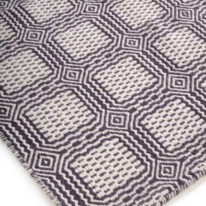 May include: A woven rug featuring a repeating geometric pattern of dark charcoal gray and off-white squares. The design consists of interconnected rounded squares with a textured, dotted interior and a thick, dark border outline throughout.