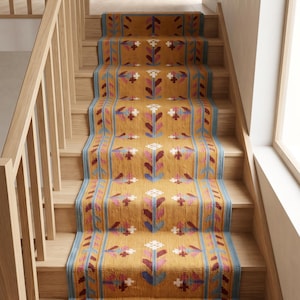 May include: A long stair runner rug featuring a mustard yellow base with a repeating floral pattern in shades of pink, blue, and white. The runner has a blue border and is installed on a wooden staircase with a light oak finish and a wooden railing.