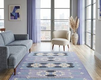May include: A rectangular area rug featuring a light periwinkle blue base with a repeating geometric pattern in shades of charcoal gray, cream, and pale blue. The design consists of symmetrical blocks and cross motifs arranged in horizontal rows.
