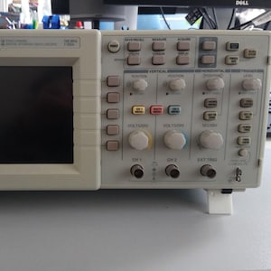 Könnte beinhalten: Ein beiges Tektronix TDS 2012 digitales Speicheroszilloskop mit schwarzem Bildschirm und zahlreichen Knöpfen und Drehreglern. Der Text "Tektronix TDS 2012" ist auf der Oberseite aufgedruckt. Es dient zur Messung und Anzeige elektrischer Signale.