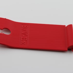 May include: Red plastic tool with a hook on one end and the text "B/V-EX" printed on the other end.