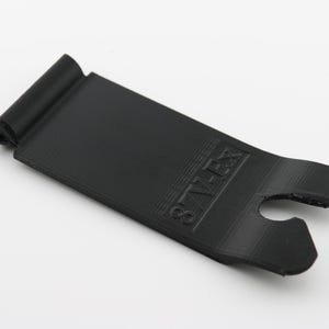 May include: Black plastic phone stand with a raised lip and a cutout for a charging cable. The stand has the word "STAY ZEN" printed on it.