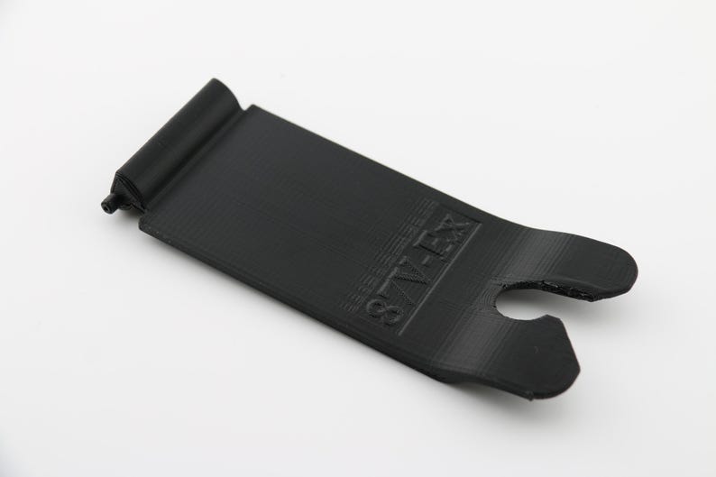 May include: Black plastic phone stand with a raised lip and a cutout for a charging cable. The stand has the word "STAY ZEN" printed on it.