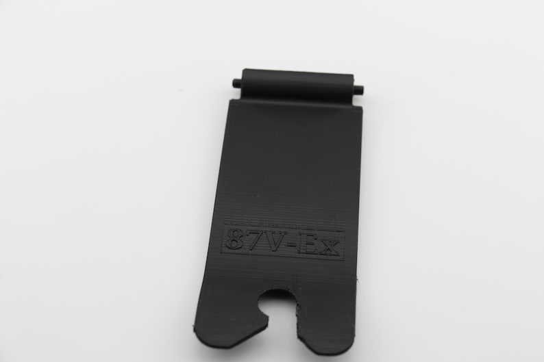 May include: Black plastic strap with a metal loop and the text "87V-EX" printed on it.