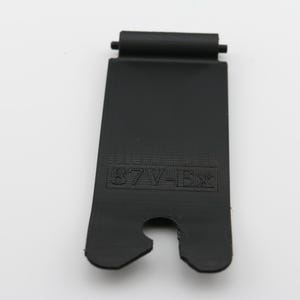 May include: Black plastic strap with a cut-out for a buckle and the text "87W-1EX" printed on it.